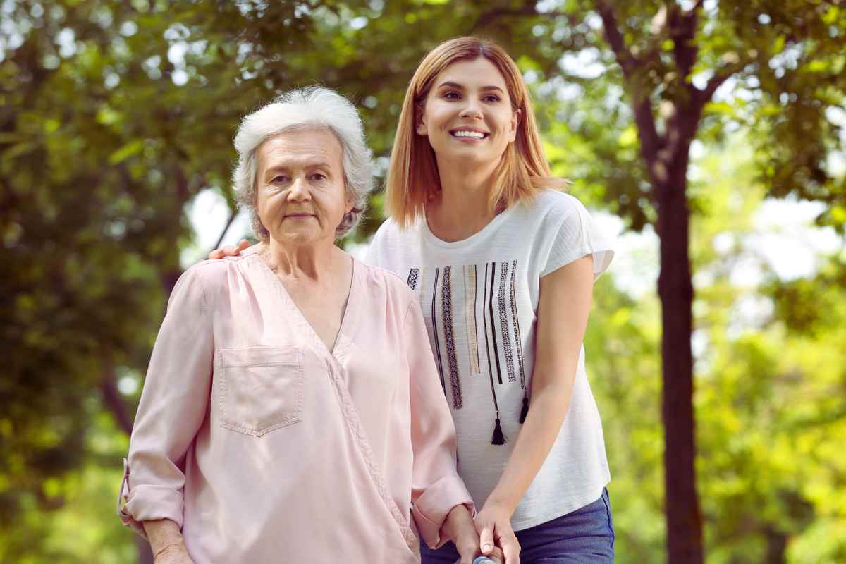 signora anziana più badante che fanno una passeggiata sorridendo