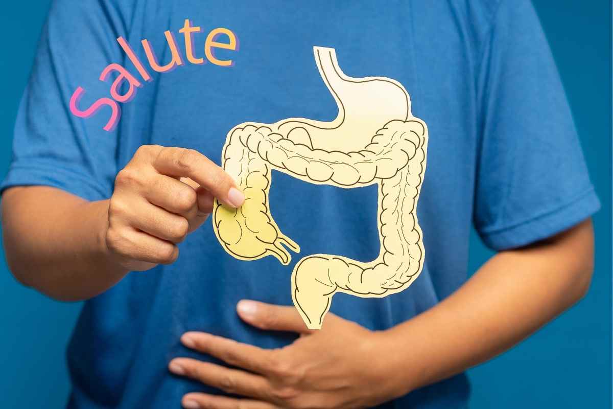 persona con una mano sulla pancia e l'altra tiene un cartoncino con rappresentato il colon