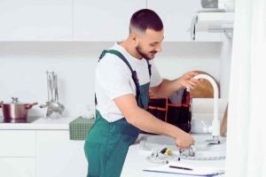 idraulico che aggiusta il rubinetto della cucina