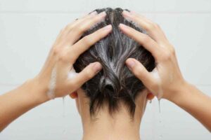 donna di spalle che si lava i capelli