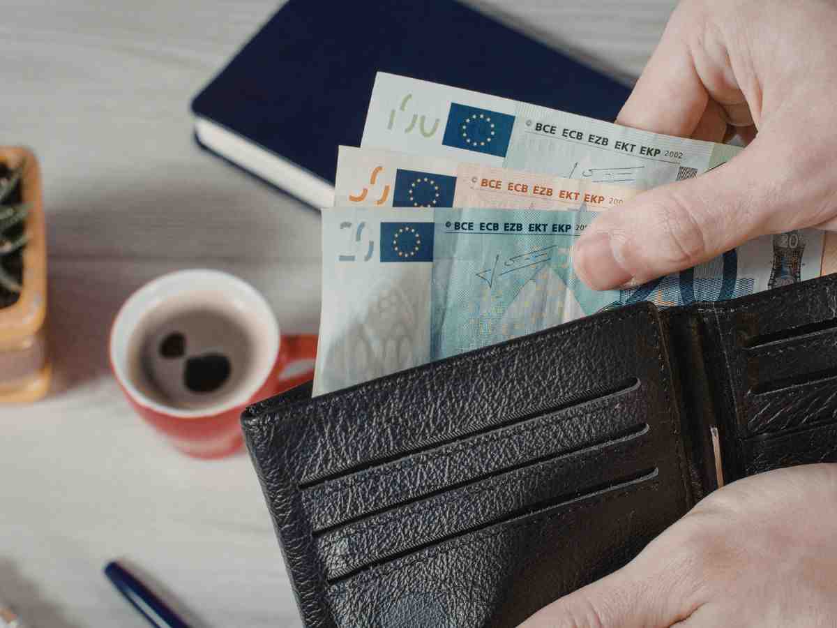 persona tira fuori dal portafogli banconote