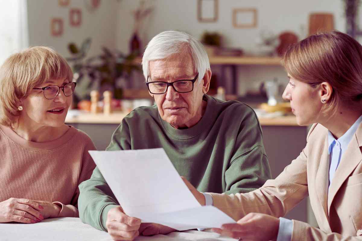 due persone anziane e una più giovane che guardano un foglio di carta